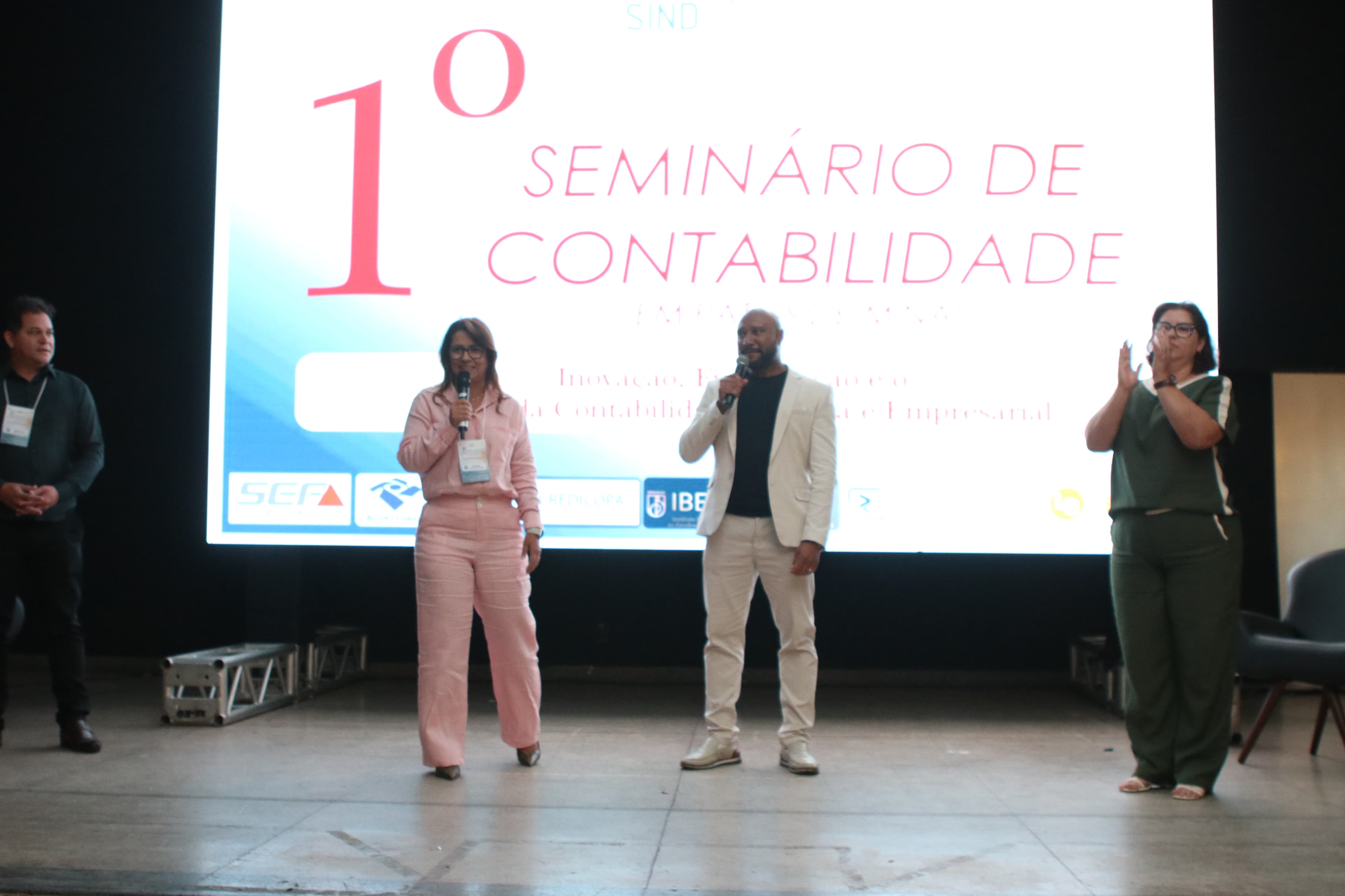 Participantes no palco em um momento de apresentação do evento